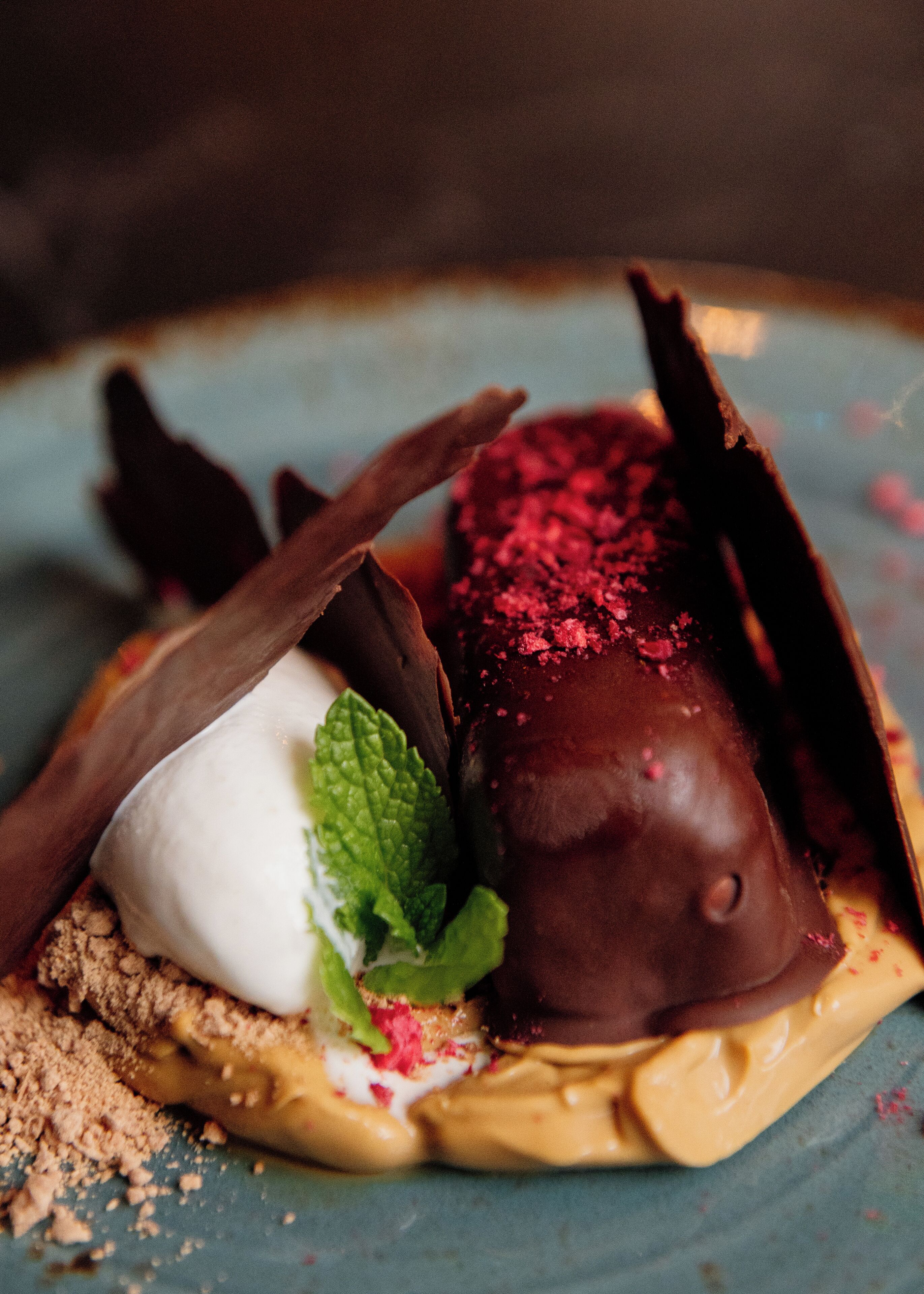 A dessert with chocolate and white elements on a plate with crumbs.