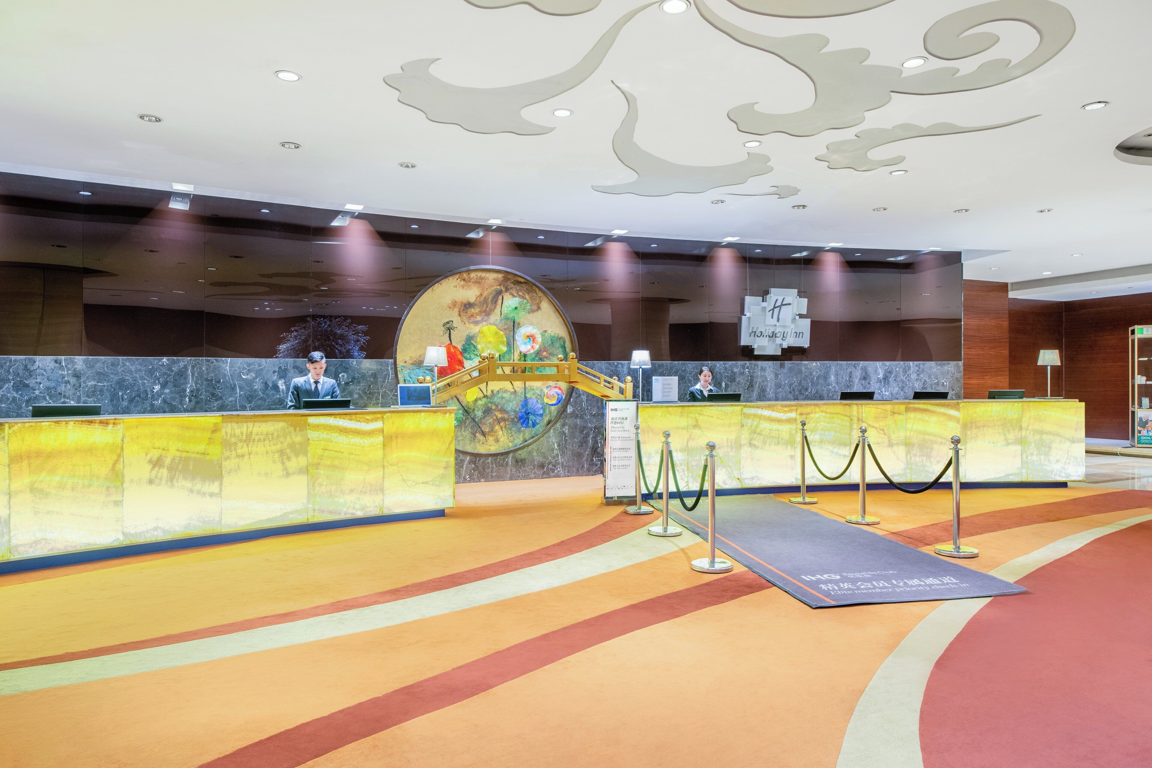 A reception area with a marble counter, a large decorative wall, and a carpeted floor.