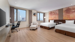A hotel room with a large bed, a smaller bed, a desk with a chair, a sofa, and a large window with a city view. - Holiday Inn Nanjing Aqua City by IHG (Nanjing)