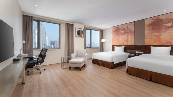 A hotel room with a large bed, a smaller bed, a desk with a chair, a sofa, and a large window with a city view. - Holiday Inn Nanjing Aqua City by IHG (Nanjing)