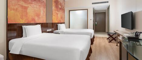 A hotel room with two beds, a desk, a TV, and a large abstract painting on the wall.