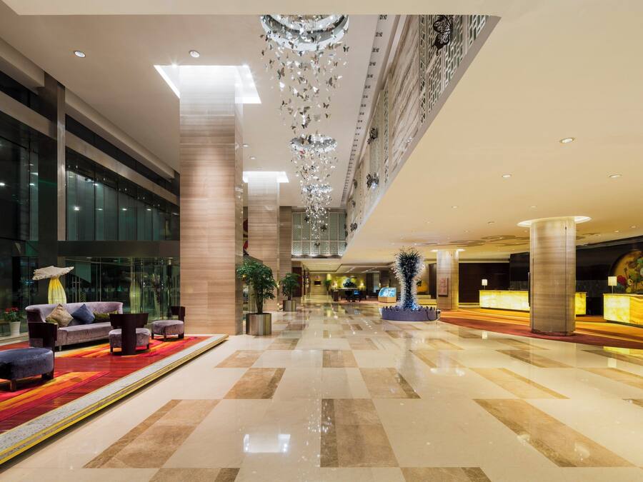 A spacious lobby with a checkered floor, a reception desk, and a seating area with sofas and chairs.