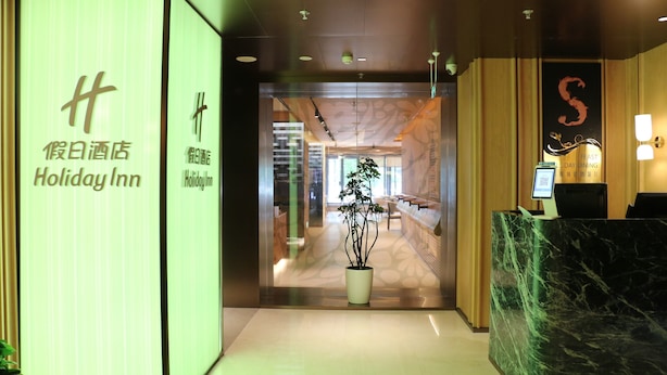 A hotel lobby with a reception desk, a potted plant, and a sign indicating it's a Holiday Inn. - Holiday Inn Nanjing Aqua City by IHG (Nanjing)