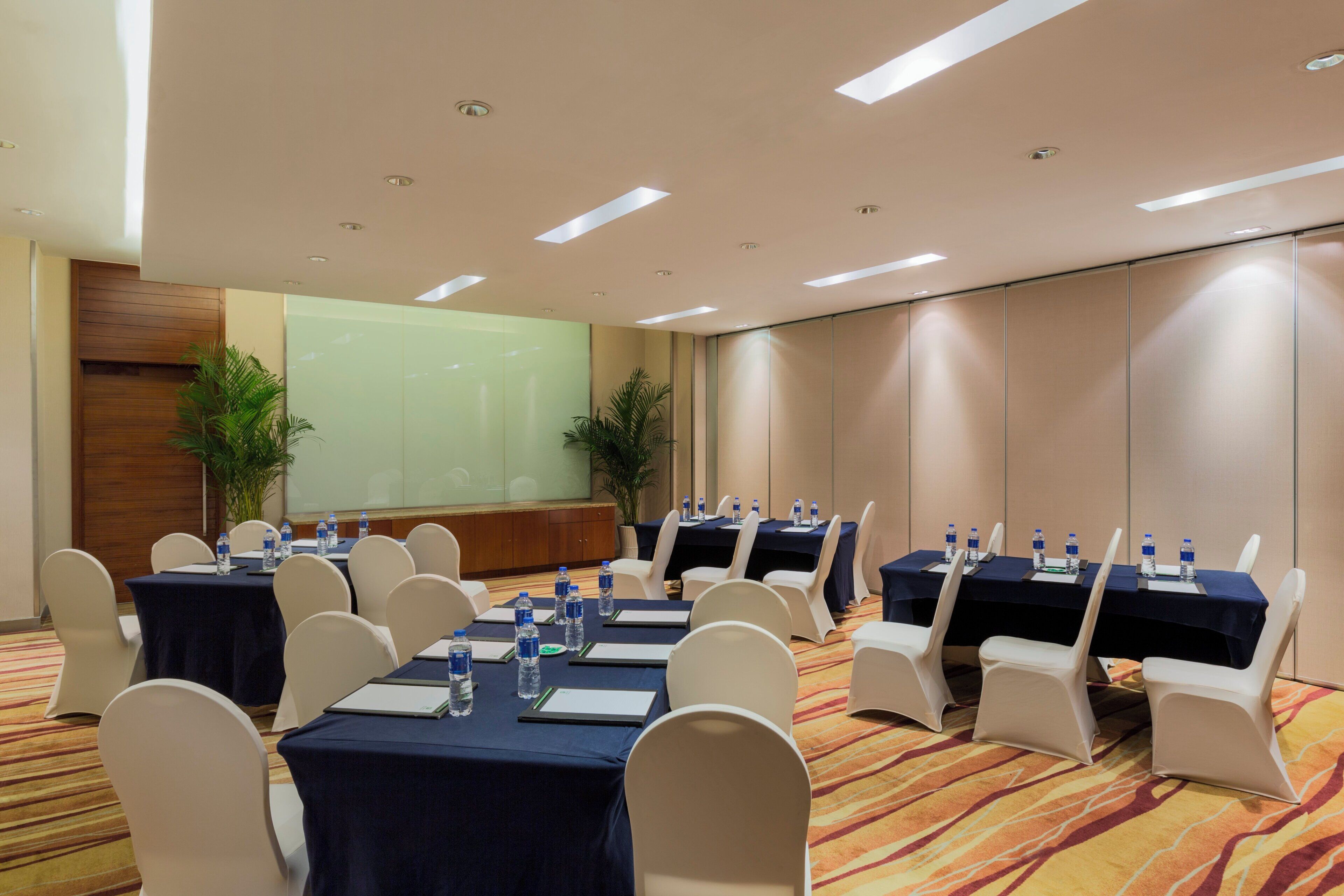 A conference room with tables set for meetings, equipped with water bottles and notepads.