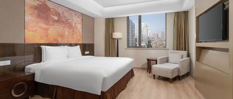 A hotel room with a large bed, a chair, a TV, a window with a city view, and a large abstract painting on the wall.