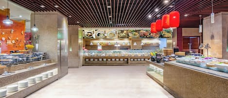 Zona de buffet con una variedad de alimentos y un mostrador con platos y cubiertos.
