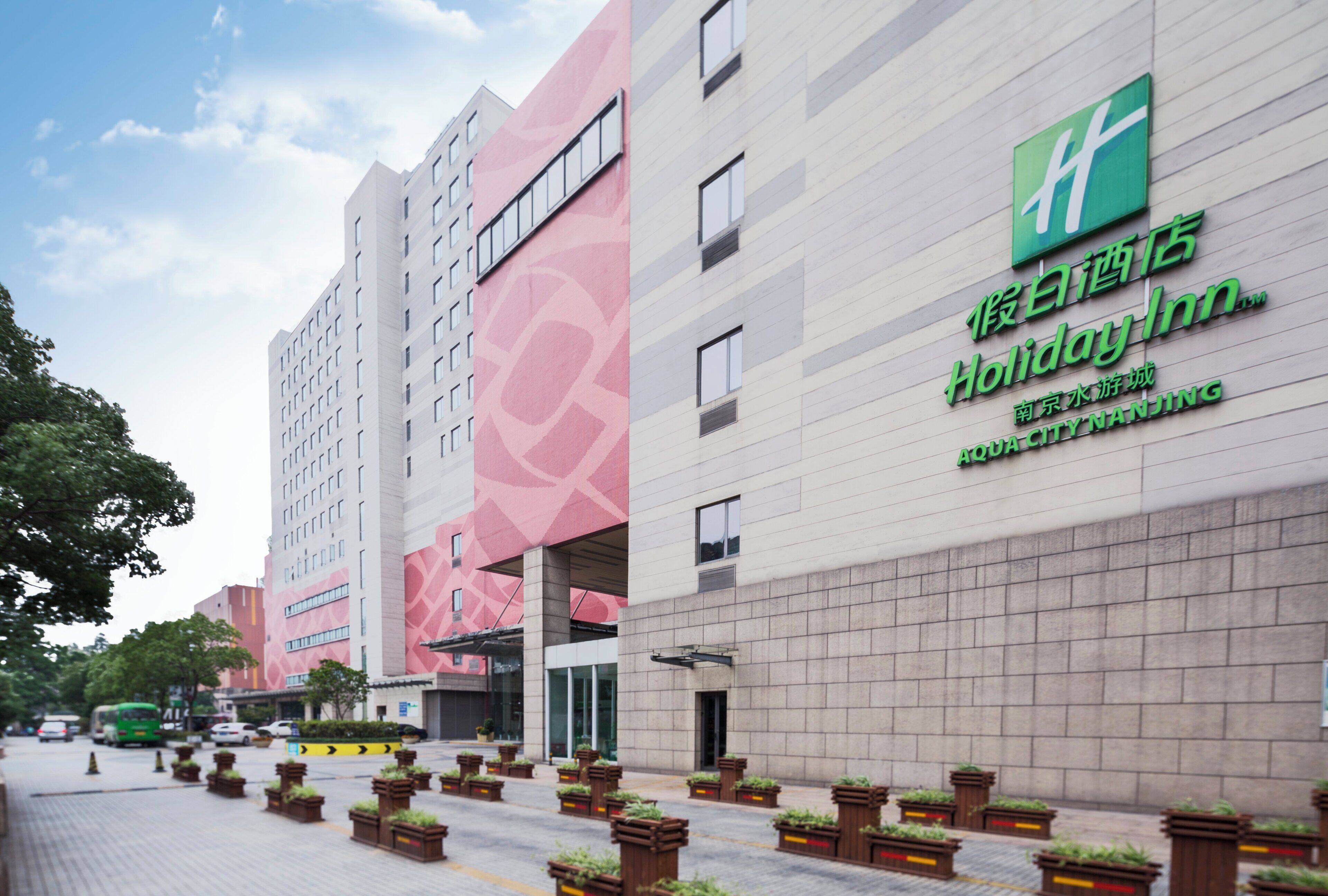 Un hotel con fachada moderna, un logotipo verde destacado y un cartel que indica que es un Holiday Inn.