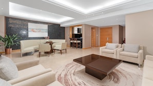 A modern living room with a sofa, armchairs, a coffee table, and a dining area with a table and chairs. - Holiday Inn Nanjing Aqua City by IHG (Nanjing)