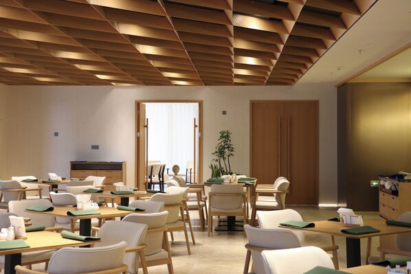 A modern classroom with wooden desks, chairs, and a large plant. - Holiday Inn Nanjing Aqua City by IHG (Nanjing)