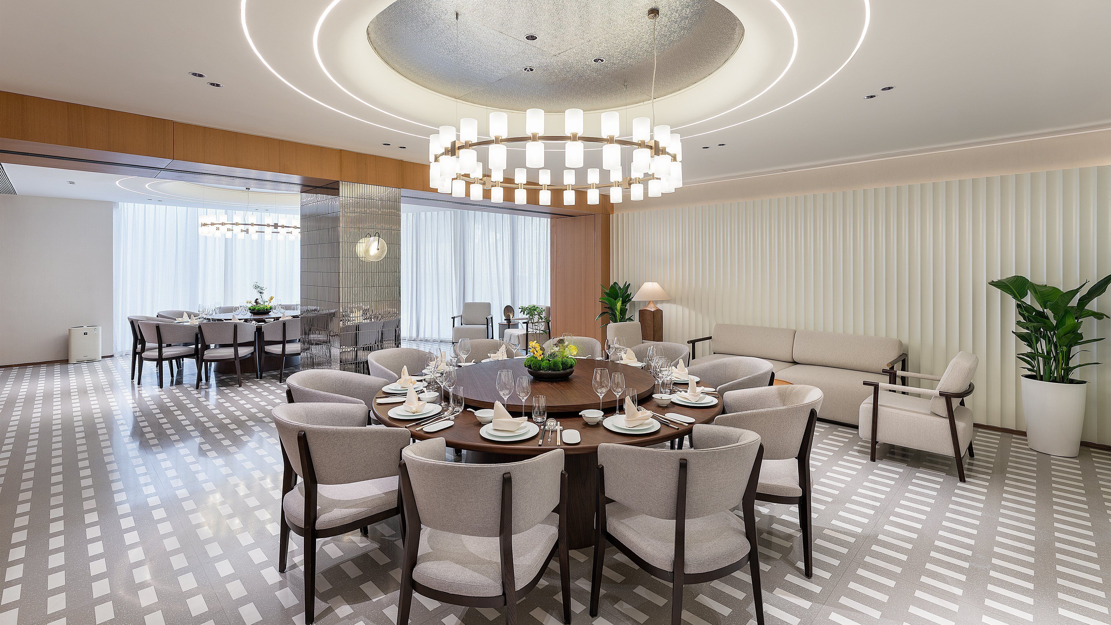 A modern hotel dining room with a round table set for a meal, surrounded by comfortable seating.