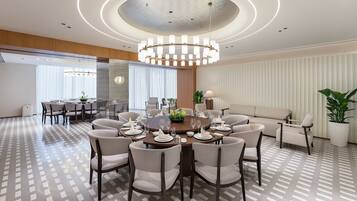 A modern hotel dining room with a round table set for a meal, surrounded by comfortable seating.