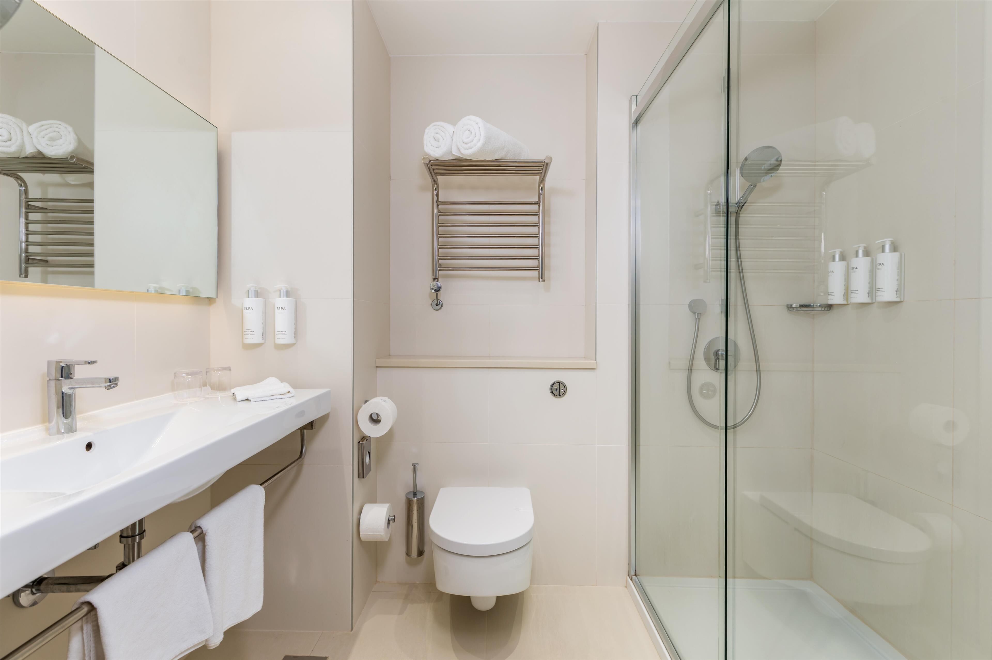 Une salle de bain moderne avec une douche à parois de verre, un lavabo blanc et des toilettes.