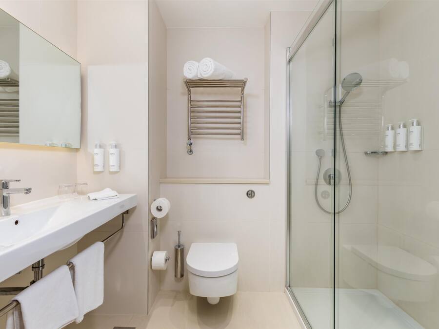 Une salle de bain moderne avec une douche à parois de verre, un lavabo blanc et des toilettes.
