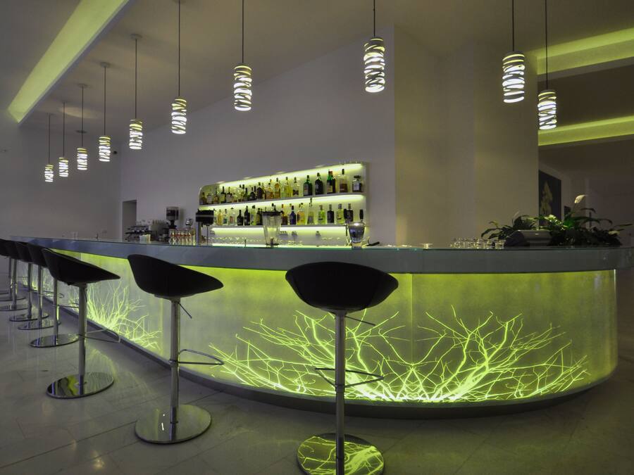 A modern bar area with a curved counter, multiple bar stools, and a neon light display.