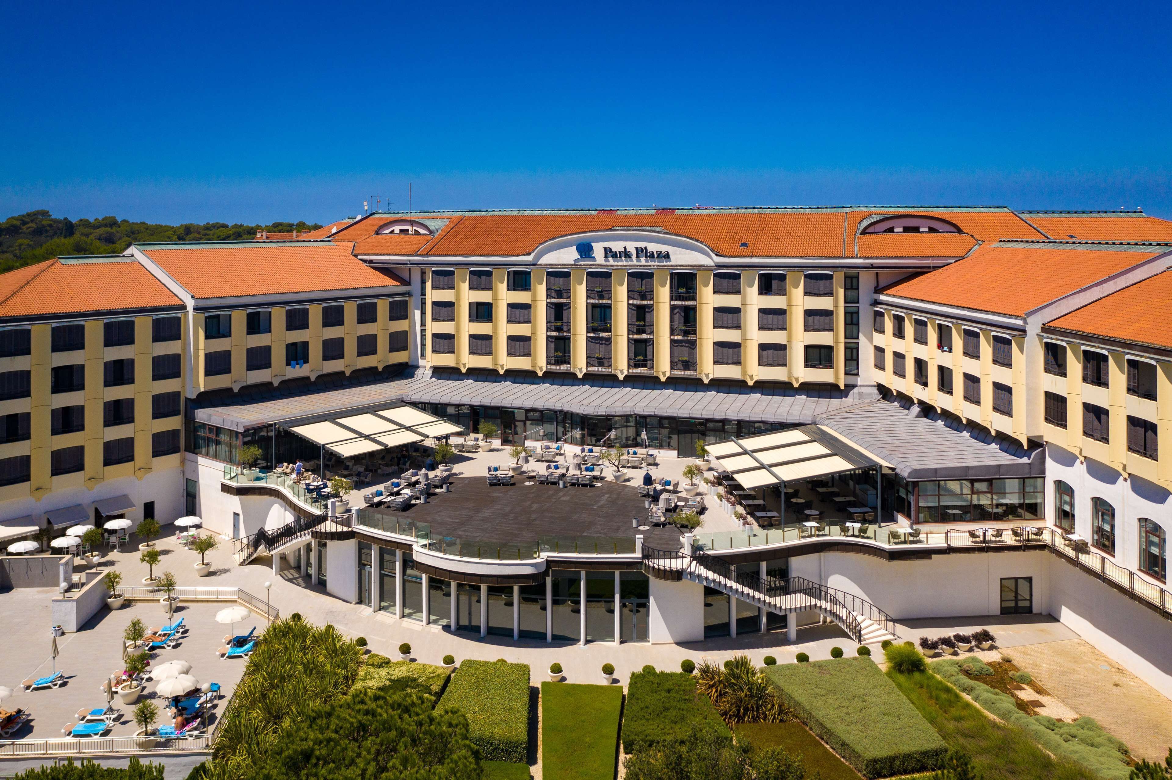 A hotel with a central courtyard, outdoor seating, and a prominent 'Park Plaza' sign.