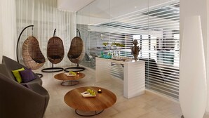 A modern living room with a sofa, two hanging chairs, a coffee table, and a kitchen area with a counter and decorative items. - Park Plaza Histria Pula (Pula)