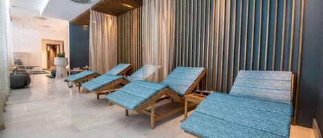 Un área de spa con sillones de madera, un espejo grande y un diseño moderno del techo.