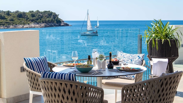 A terrace with wicker furniture, a table set for dining, and a view of the sea with boats. - Park Plaza Histria Pula (Pula)