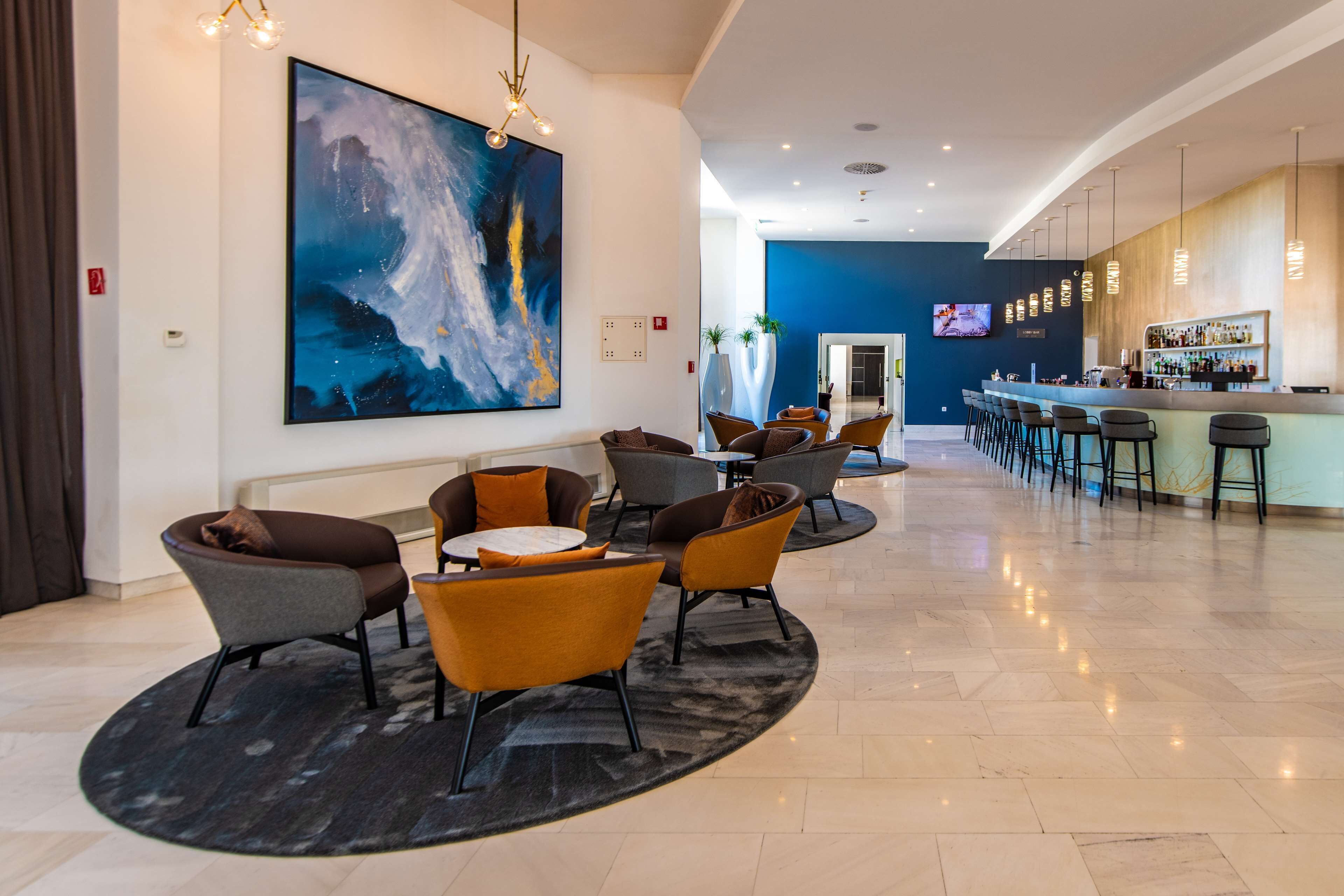 A modern lobby with a large abstract painting, a bar area, and seating arrangements.