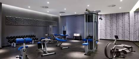 Un gimnasio moderno con diversos equipos de ejercicio, incluyendo mancuernas, máquinas de pesas y una máquina de remo.