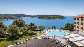 A resort with a large pool, lounge chairs, and a view of the sea. - Park Plaza Histria Pula (Pula)