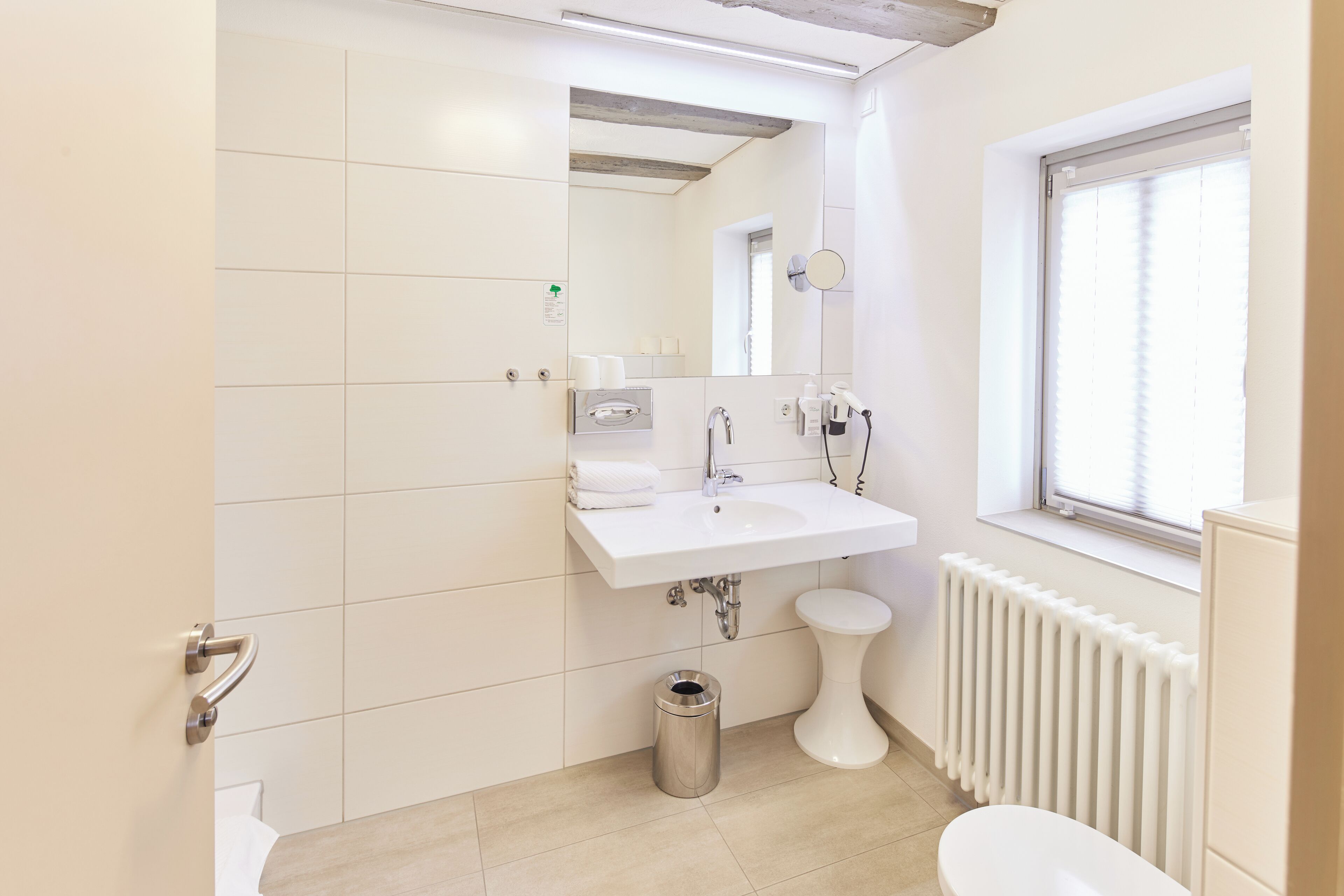Un bagno moderno con lavandino, specchio e vaso bianco.