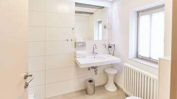 Un bagno moderno con lavandino, specchio e vaso bianco.