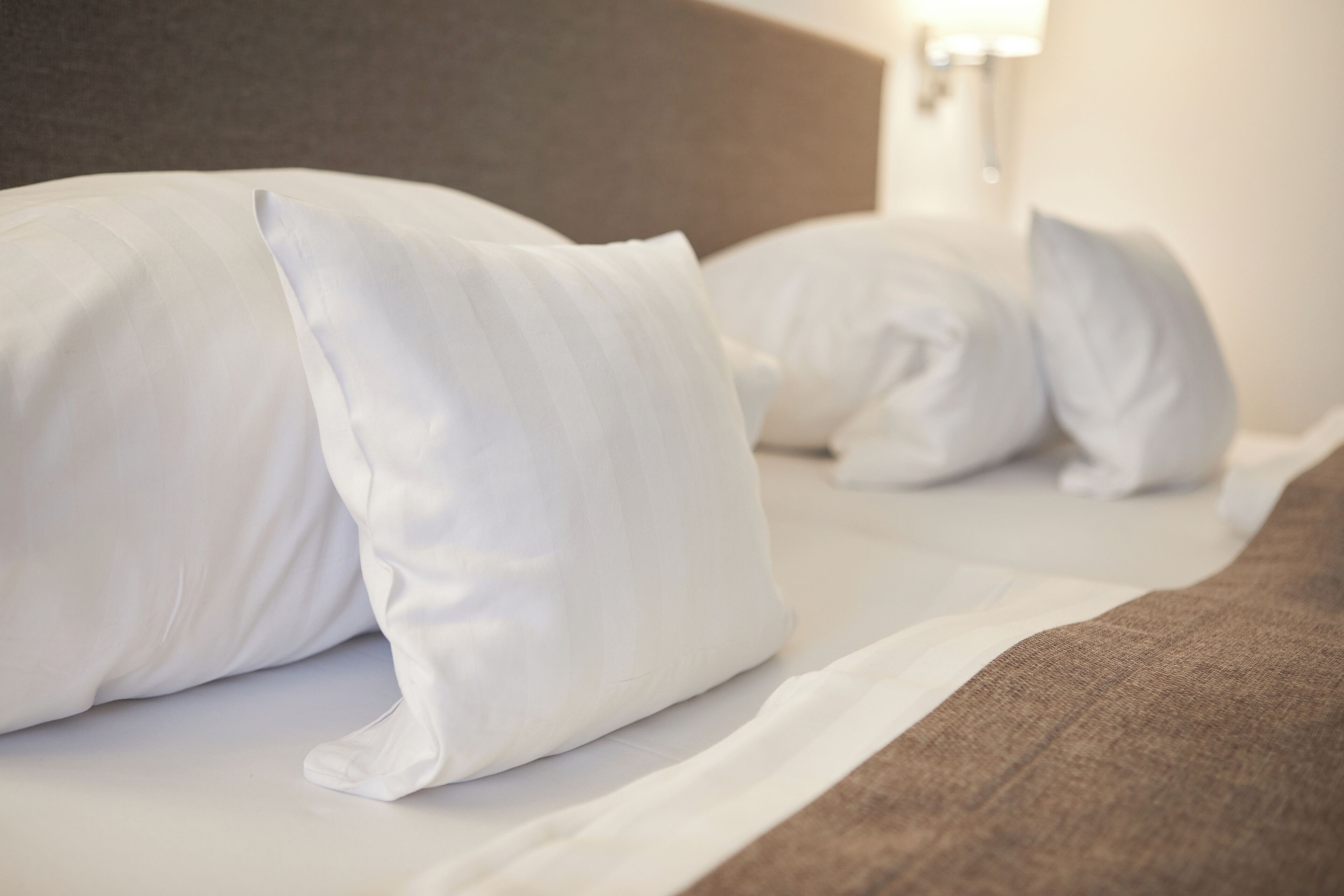 Una cama bien hecha, con almohadas blancas y un cabecero marrón.