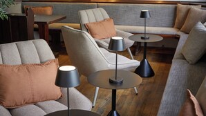 Ein stilvoller Lounge-Bereich mit Sofas, Sesseln und runden Tischen mit Lampen.