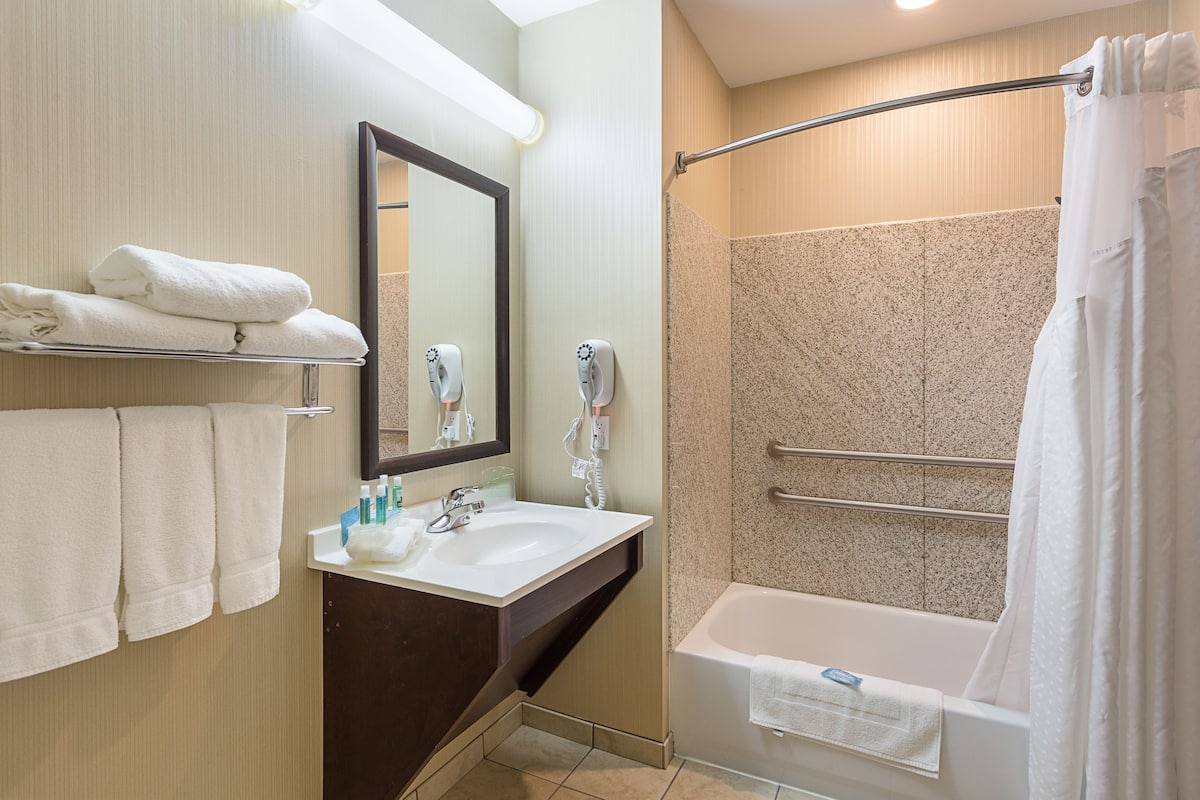 Une salle de bain moderne équipée d’un lavabo, d’un miroir, d’un porte-serviettes et d’une douche à l’italienne.