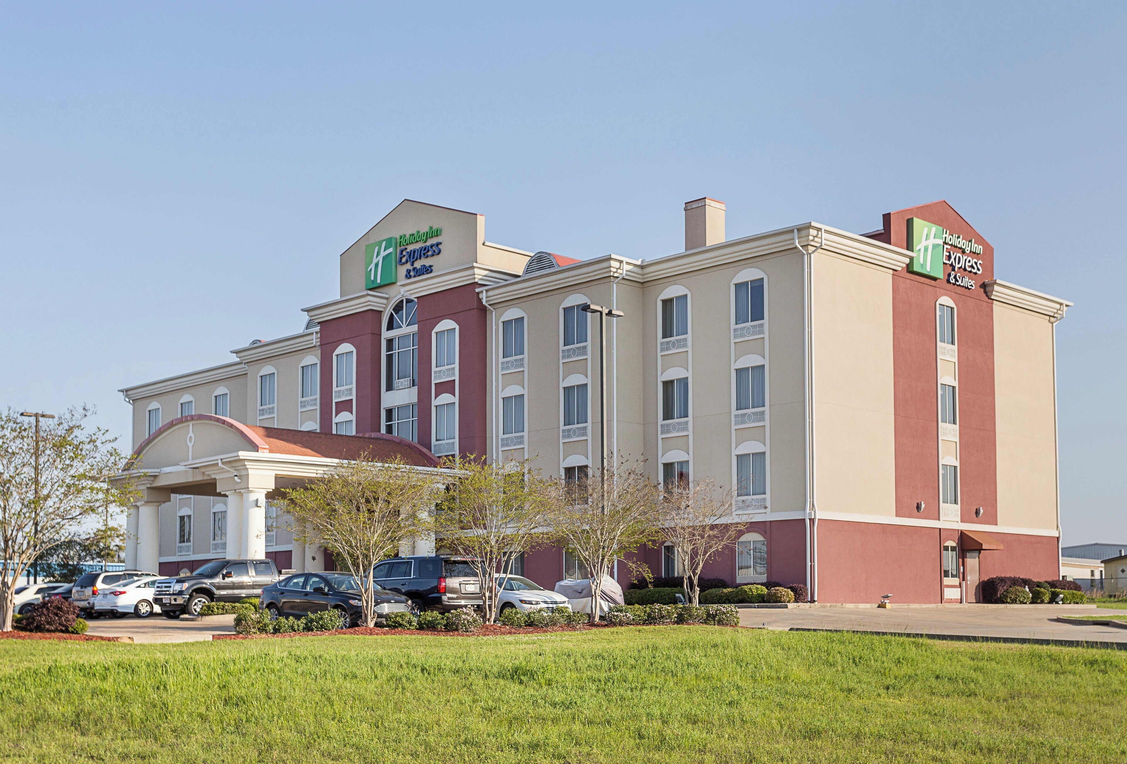 Ein Holiday Inn Express Hotel mit zentralem Eingang, mehreren Etagen und einem Parkplatz.