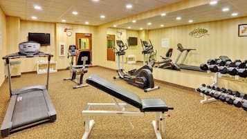 A gym with various exercise equipment including treadmills, an elliptical, and dumbbells.