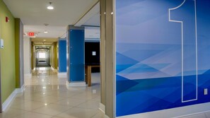 A hallway with a blue geometric wall design, an exit sign, and a tiled floor.
