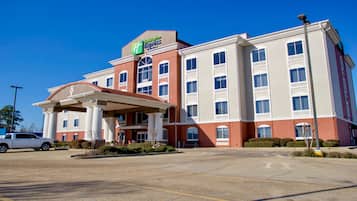 Um hotel Holiday Inn Express com entrada central, vários andares e estacionamento.