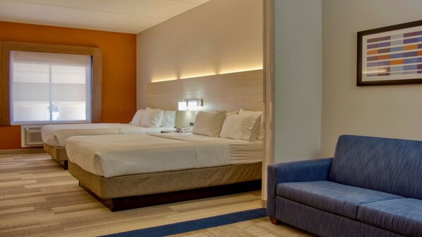 A hotel room with two beds, a blue armchair, a large window, and a framed artwork on the wall. - Holiday Inn Express Hotel & Suites BYRAM by IHG (Byram)