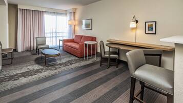 A hotel room with a sofa, chairs, a small table, and a desk.
