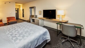 Une chambre d’hôtel comprenant un lit, un bureau, une chaise, une télévision et une lampe.