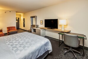 Une chambre d’hôtel comprenant un lit, un bureau, une chaise, une télévision et une lampe.