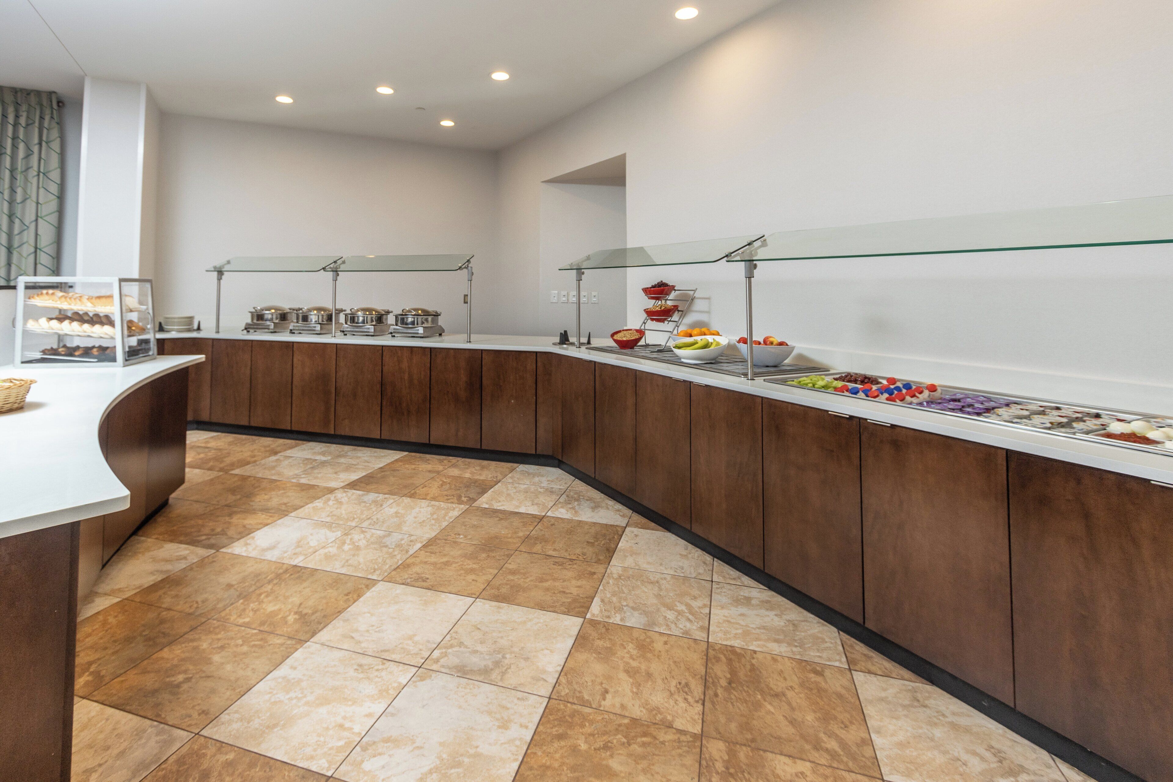 A buffet area with a variety of food items, a glass display case, and a tiled floor.