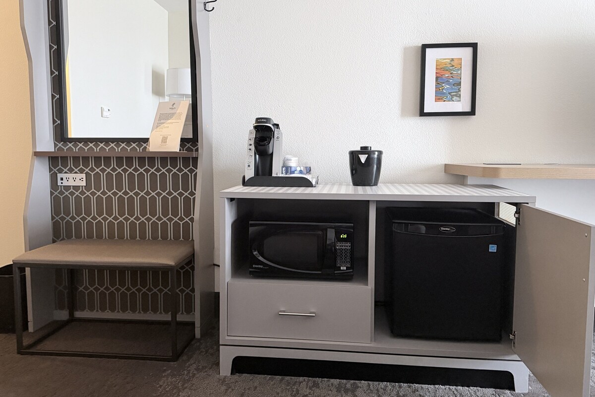 Une petite cuisine équipée d’un four à micro-ondes, d’une machine  à café et d’un petit placard.