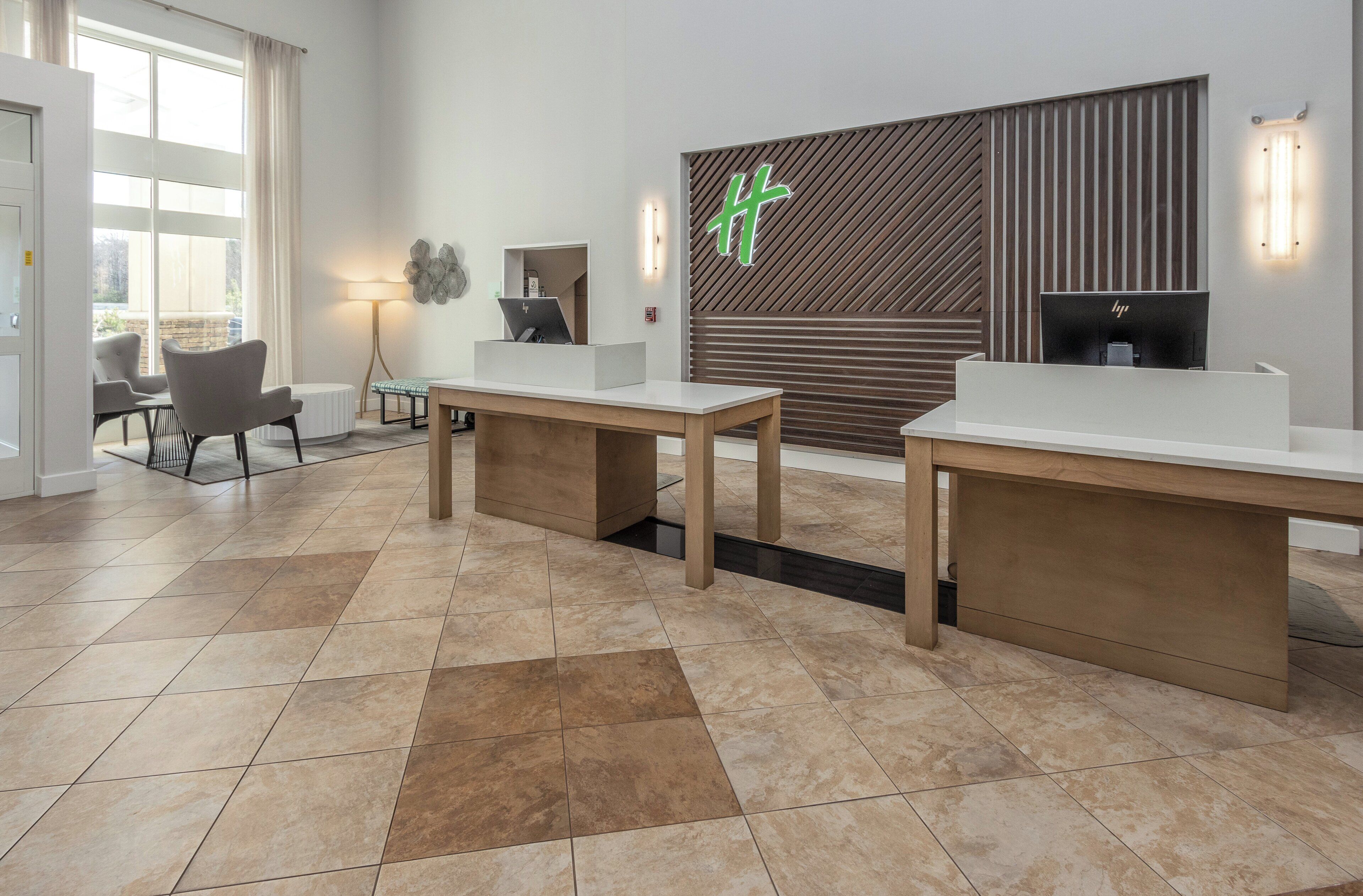 A reception area with two reception desks, a large window, and a wall-mounted sign.