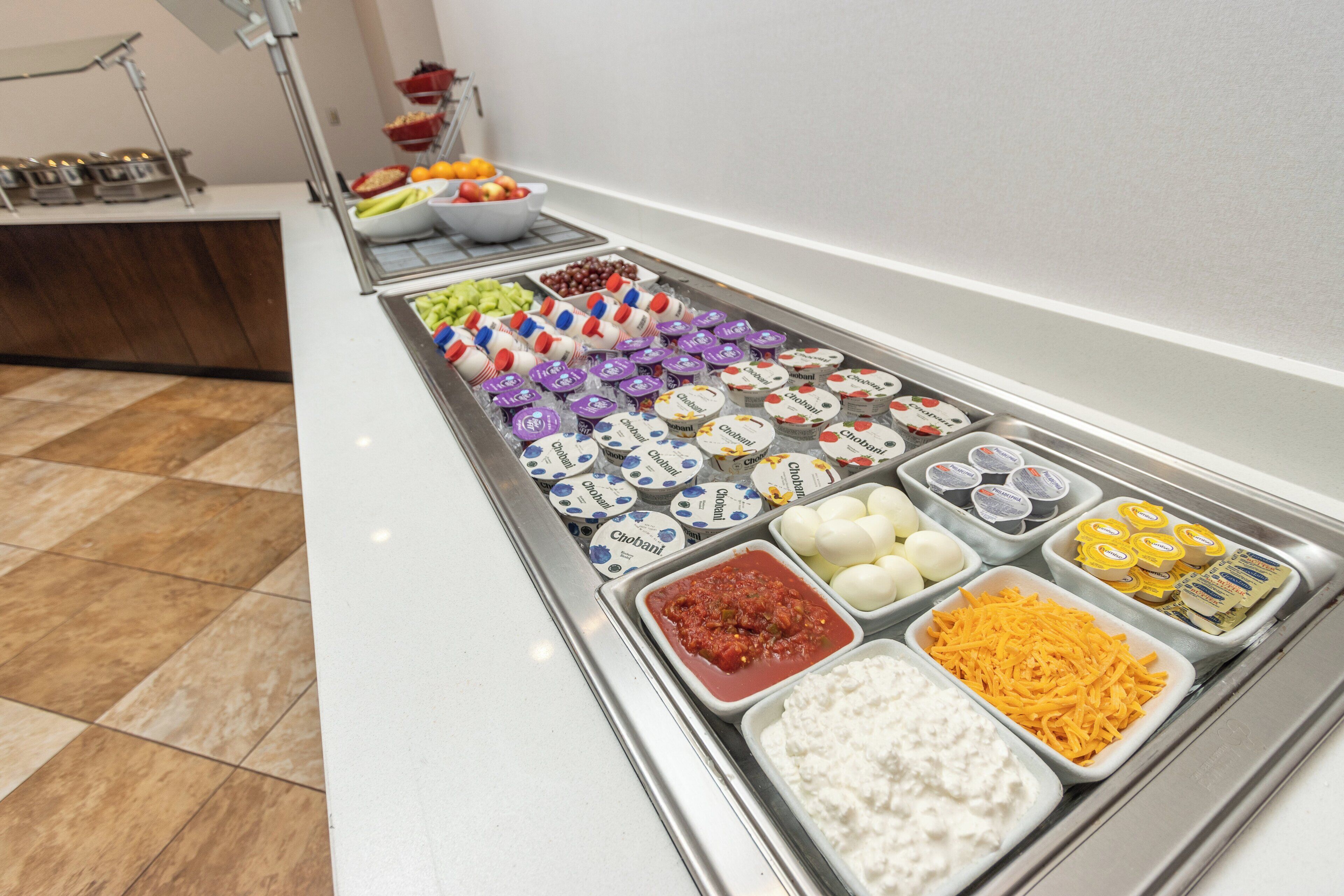 Una mesa de buffet con diversos alimentos, como frutas, quesos y salsas.
