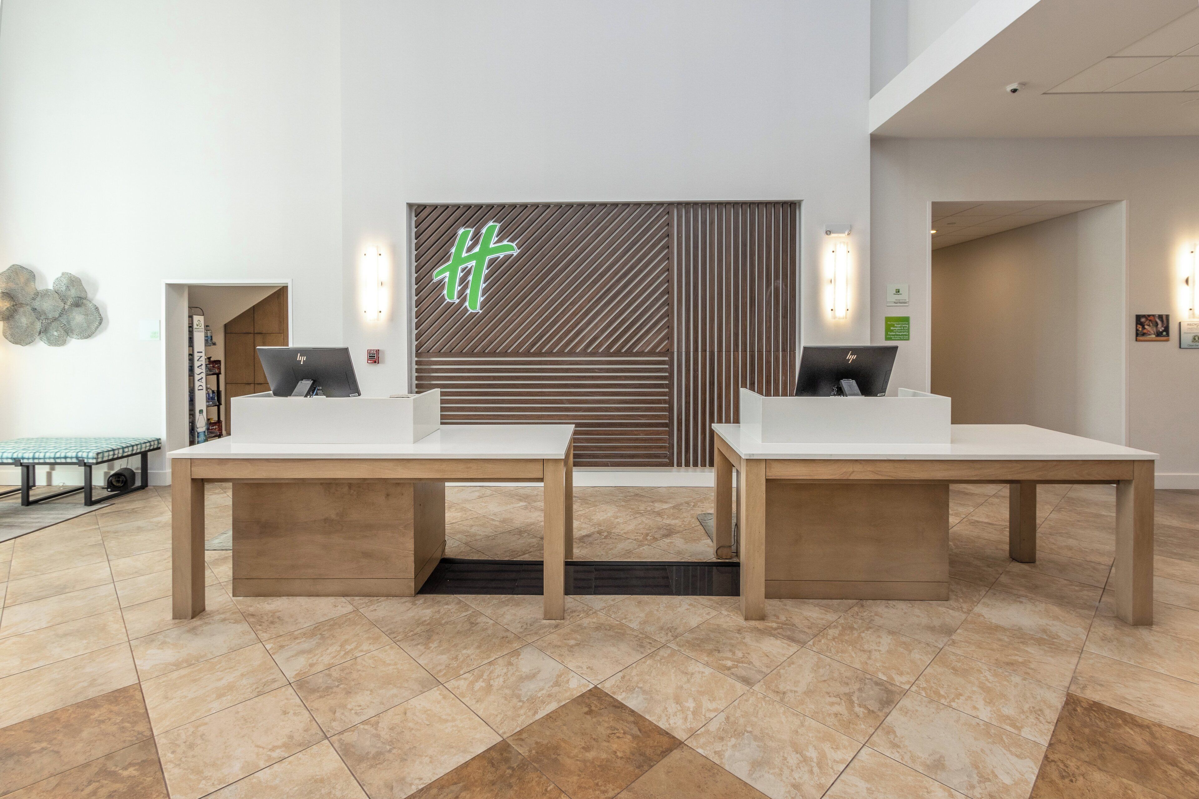 A reception area with two reception desks, a modern wall design, and a tiled floor.
