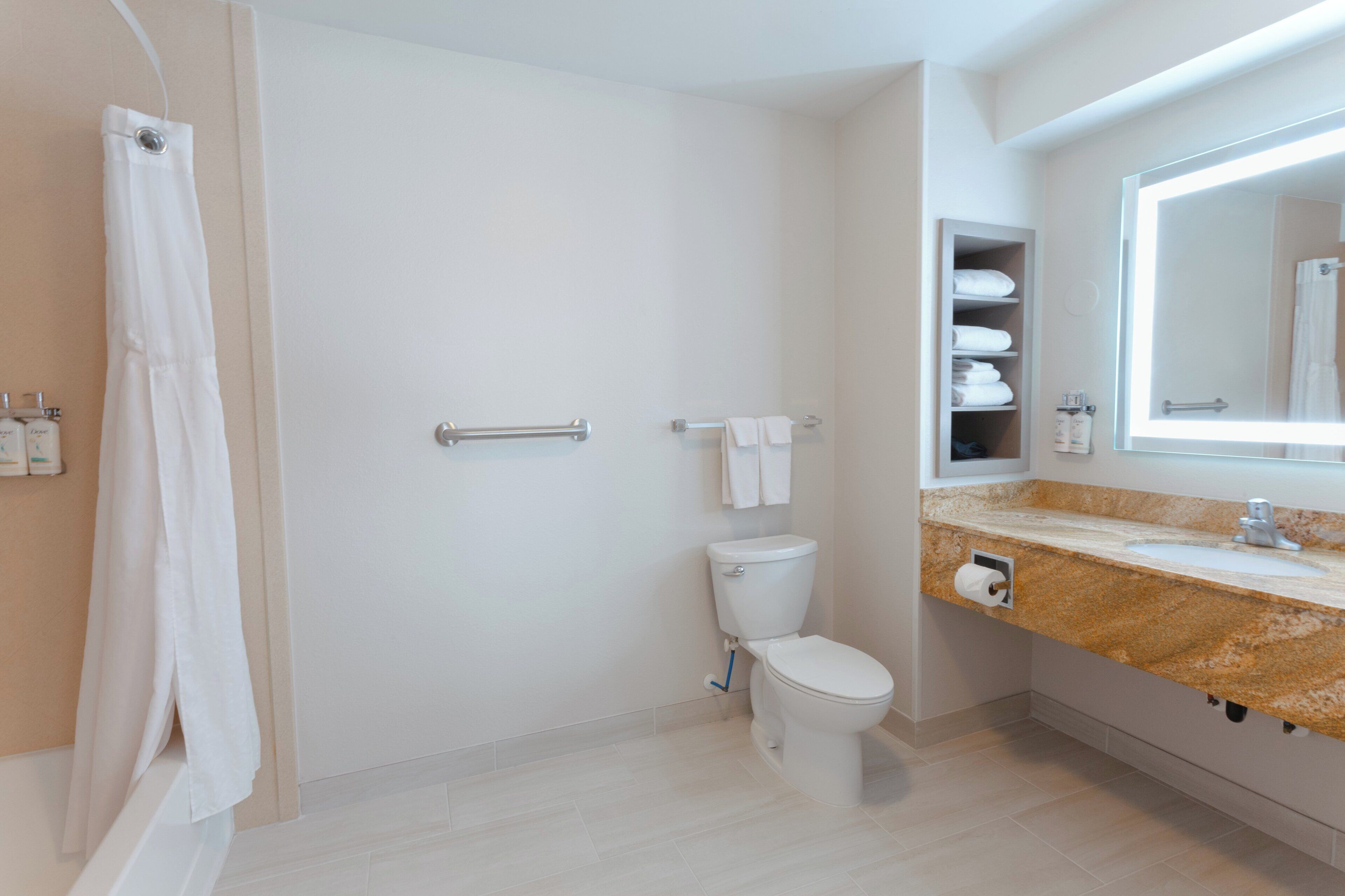 A modern bathroom with a toilet, a shower curtain, a towel rack, and a vanity with a mirror.