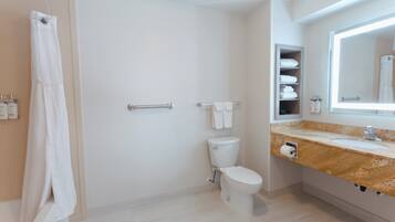 A modern bathroom with a toilet, a shower curtain, a towel rack, and a vanity with a mirror.