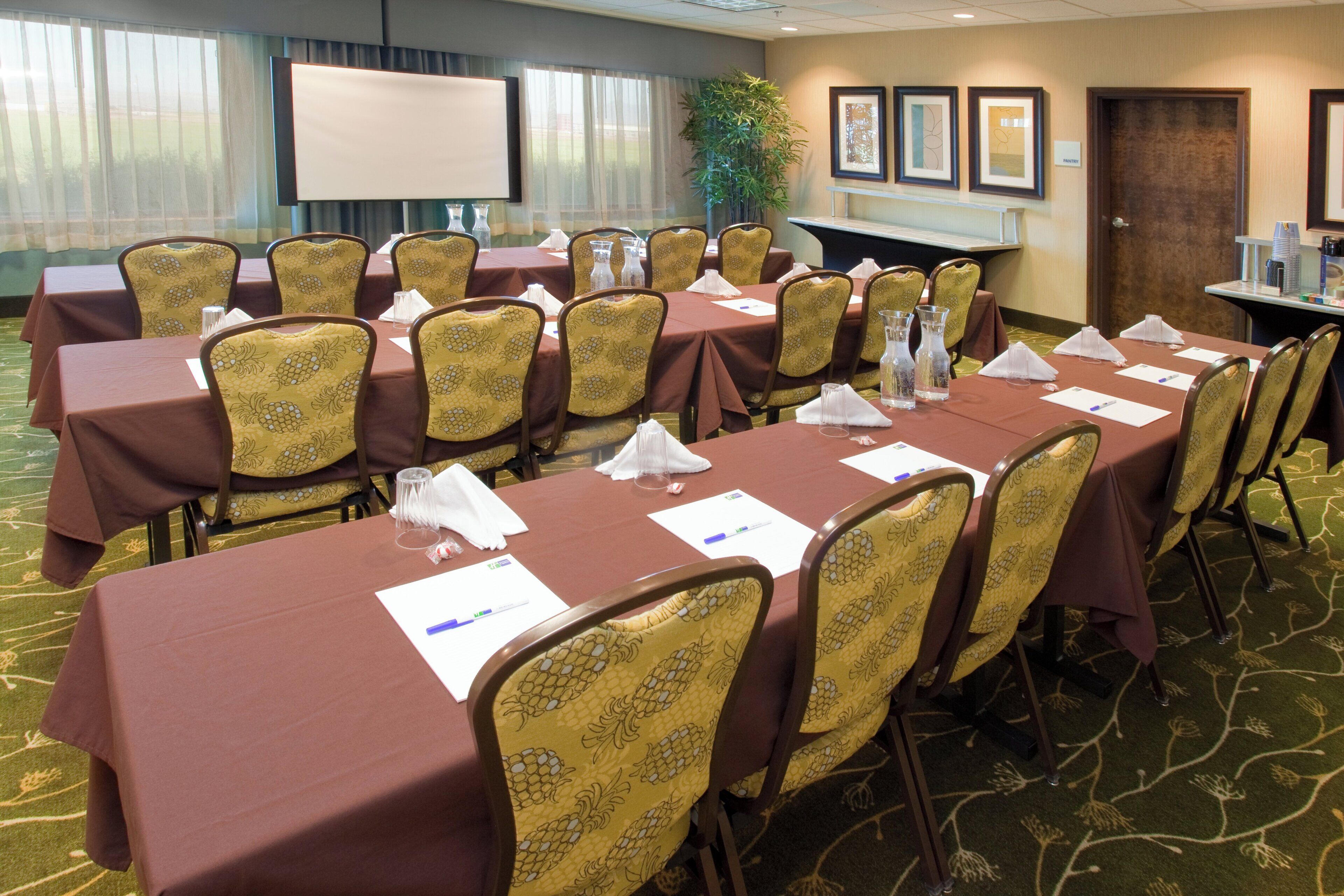 A conference room with tables set for meetings, equipped with nameplates, water glasses, and notepads.