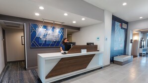 Modernilla designilla varustettu vastaanottotiski, jossa on digitaalinen näyttö ja kyltti, jossa näkyy hotellin nimi.