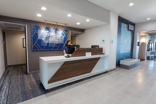 A reception desk with a modern design, a digital screen, and a sign indicating a hotel name.