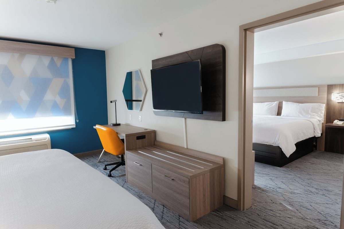 A hotel room with a bed, a desk, a chair, a TV, and a bedside table.