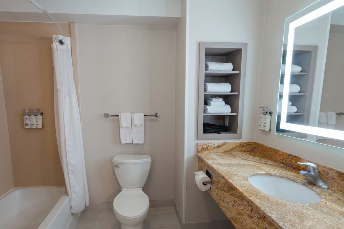 A bathroom with a bathtub, toilet, sink, and a towel rack with towels.